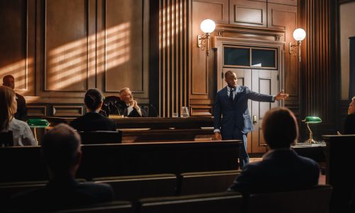 Court of Justice and Law Trial: Male Public Defender Presenting Case, Making Passionate Speech to Judge, Jury. African American Attorney Lawyer Protecting Client's Innocents with Supporting Argument.
